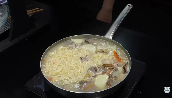 Add kalguksu noodles, eobak, green onions, and cheongyang peppers to the broth and boil until noodles are cooked.