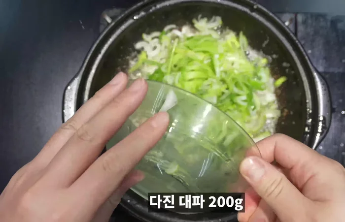 Add chopped green onions and red pepper powder to the remaining oil in the pan and stir-fry briefly.