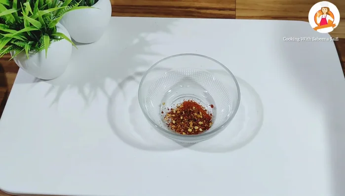 Prepare the spice mixture: In a bowl, combine red chilli powder, crushed red chilli flakes, sugar, and crushed black pepper. Mix well.