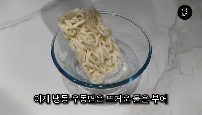 Pour hot water over the frozen noodles and drain them, letting them dissolve well.