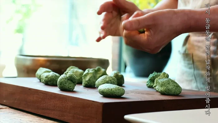 Roll small portions of dough into flat cakes.