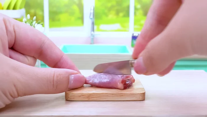 Gently score the surface of the chicken thigh with a knife.