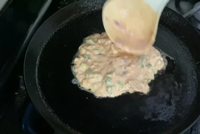 Pour a ladle full of batter onto the pan and spread it into a pancake shape.