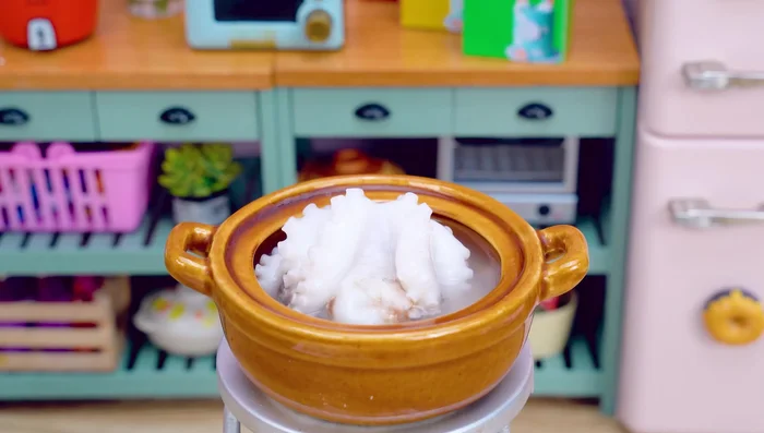 Put the octopus into the pot of water. Wait for 10 minutes. Take it out. Cut off the octopus head. Slice the octopus tentacles.