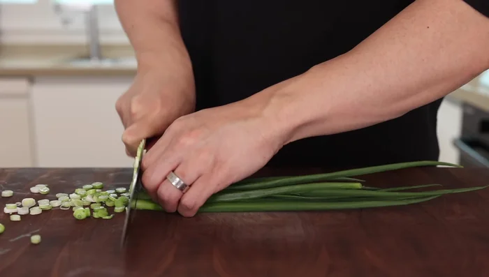 Thinly slice three green onions, separating the whites and greens.