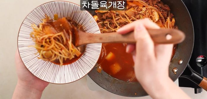 Prepare the broth: Combine beef broth, gochujang, gochugaru, soy sauce, minced garlic, and ginger in a pot. [This step is inferred based on the audio; specific quantities are not provided]