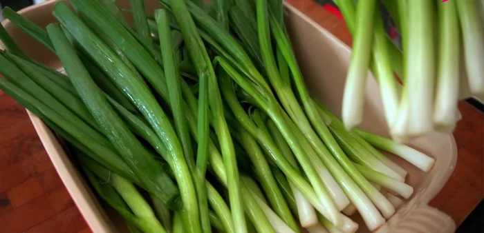 Prepare green onions (Part 2): After 30 minutes, remove green onions from brine, place them on a baking tray, and pour the brine over the green parts. Weigh down the green parts with a plate for 15 minutes to 2 hours, mixing halfway through.