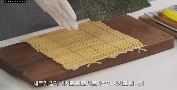 Prepare the kimbap: Lay a sheet of kim on the rolling mat, add rice, carrots, and seasoned tofu.