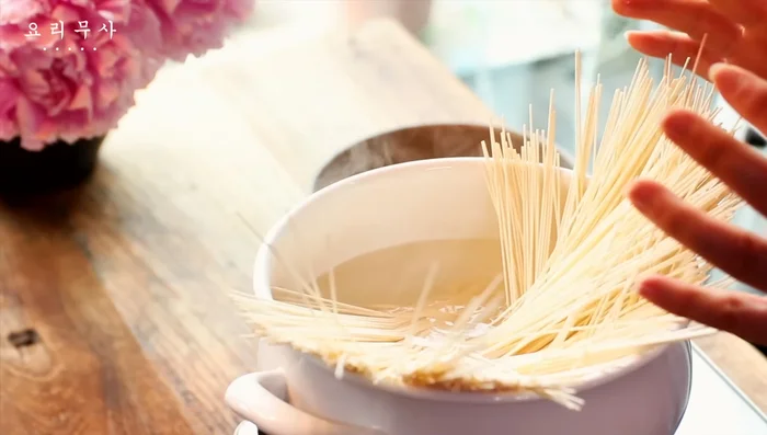 Add a little salt to the boiling water and boil the noodles for about 3 minutes, adding cold water as they boil three times. When cooked and transparent, rinse them in cold water, drain them in a colander, and drain.