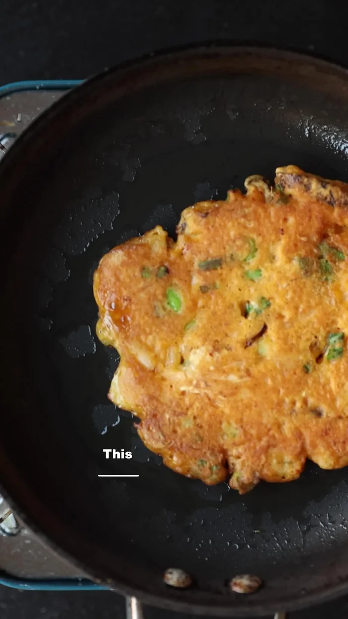 Cook the kimchi pancake batter in the hot oil until golden brown and crispy.