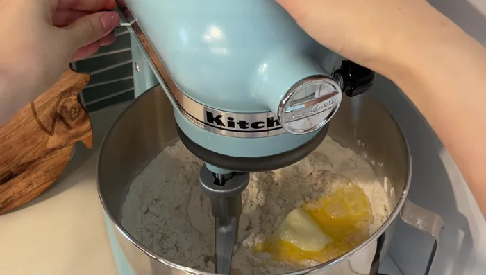 Add water, beaten egg, and softened butter. Mix on low until combined. Then, use a dough hook and knead for 8-10 minutes until smooth and slightly tacky.