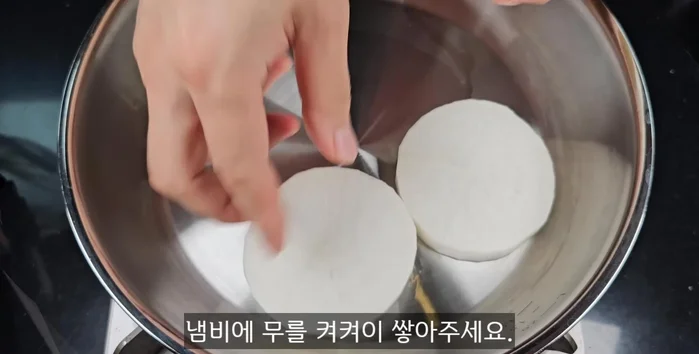 In a pot, layer the sliced radish, then onions, and top with shiitake mushrooms.