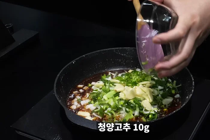 Add chopped onion, green onion, garlic, green chili pepper, and red chili pepper. Stir-fry until the onion is translucent.