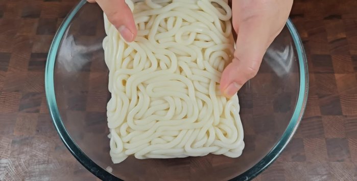Prepare two servings of udon noodles. Put them in a mixing bowl and pour hot water over them. Let them soak until soft.