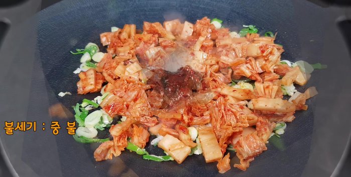Add the sliced kimchi and season with 1 spoon of red pepper paste, 2 spoons of tuna liquid, and 1 small spoon of sugar. Stir-fry.