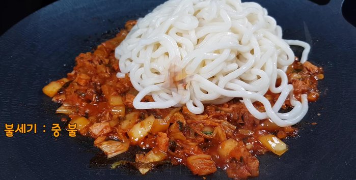 Add the udon noodles and stir-fry over medium heat, ensuring they don't stick to the pan.