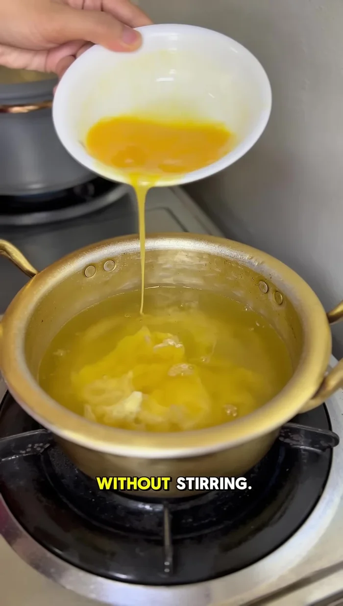 Back to the soup. Slowly pour in the beaten eggs without stirring. This helps reduce bubbles and keeps the texture smooth.