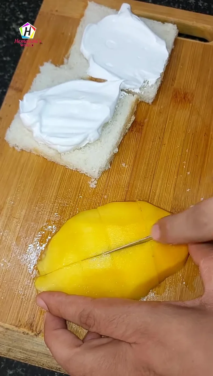 Spread whipped cream on one slice of bread, add mango chunks, top with another slice of bread, and spread more cream on top.