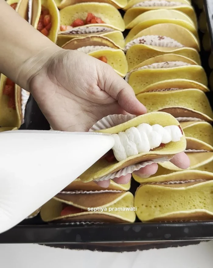 Assemble Strawberry Pancakes: Place strawberry pieces on the bottom of a folded pancake, fill with whipped cream, and top with sliced strawberries.