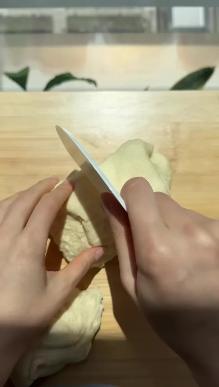 Once the dough has risen, divide it equally and roll each piece into a smooth ball.