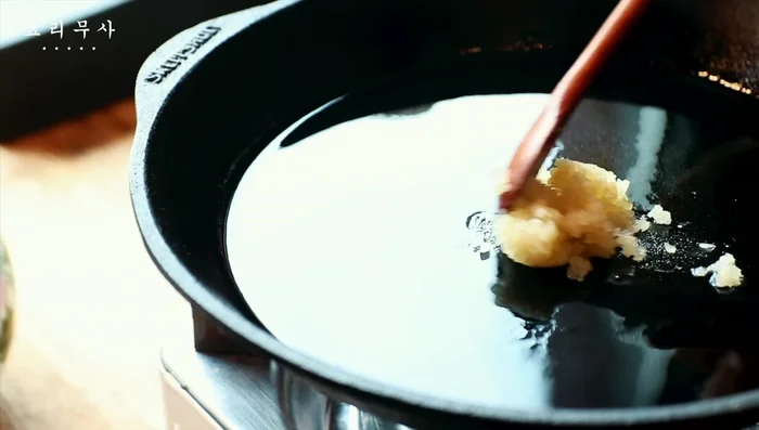 Heat cooking oil and sesame oil in a pan. Add garlic, green onions, and dried chili peppers for flavor.
