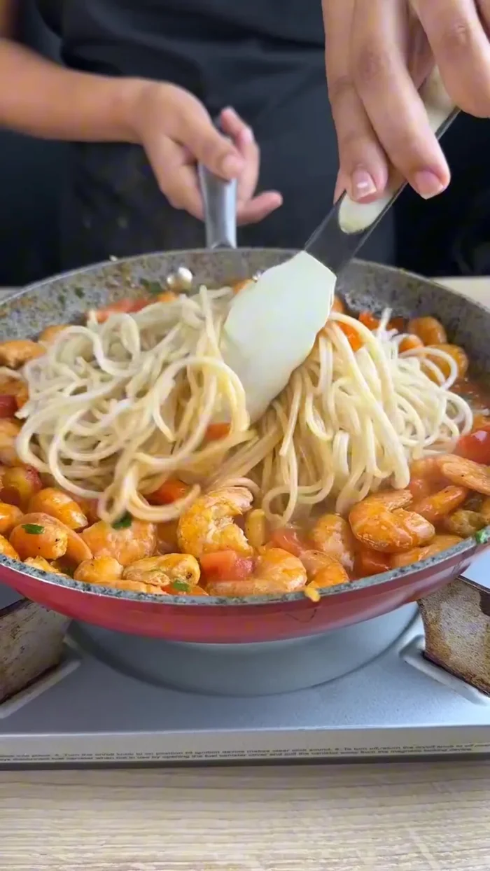 Add 7 oz of cooked pasta and mix thoroughly with the sauce and shrimp. Ensure everything is well incorporated.