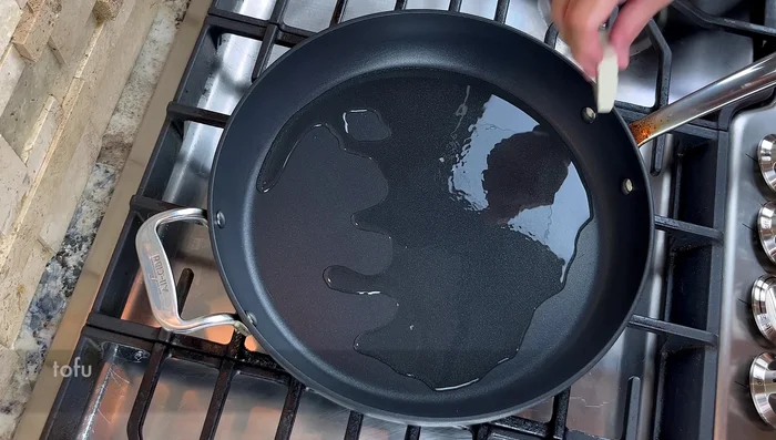 Heat oil in a pan. Pan-fry tofu until golden brown on both sides, seasoning lightly with salt.