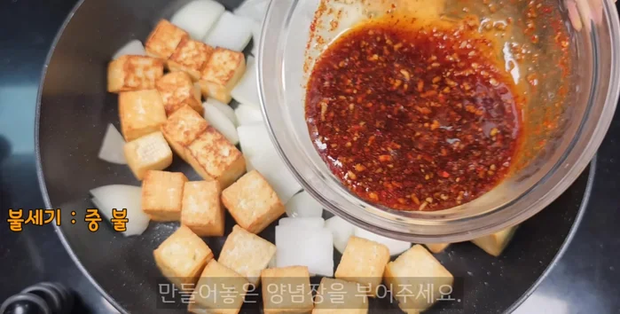 When the last side of the tofu starts to turn brown, pour in the seasoning sauce.
