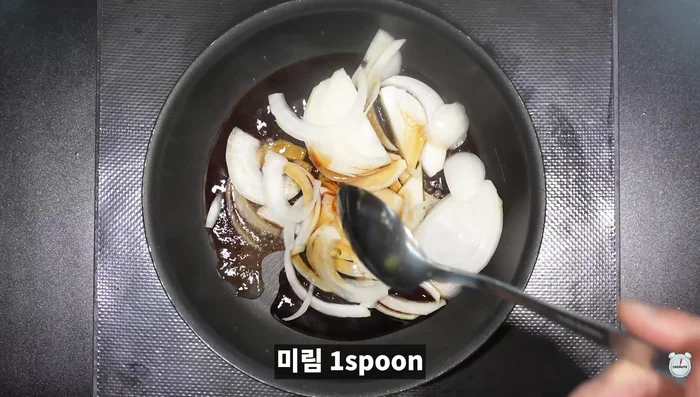 Rice bowl assembly: Place the grilled tteokgalbi on rice. Pour a sauce made from chopped onions, water, soy sauce, mirin, and sugar over the tteokgalbi. Add scrambled eggs and sprinkle with basil.