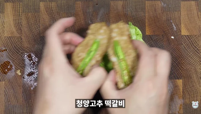 Burger assembly: Spread ketchup and mayonnaise on the inside of the hamburger bun. Add halved lettuce, tteokgalbi, and a fried egg. Spread ketchup and mayonnaise on the burger lid and cover.