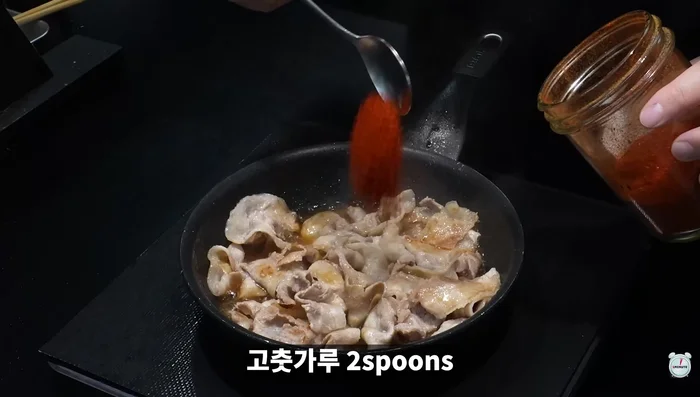 Add soy sauce, red pepper powder, red pepper paste, minced garlic, carrots, onions, and green onions to the cooked pork belly and stir-fry.