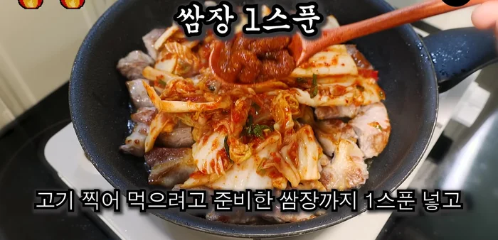 Add 3 spoons of kimchi and 1 spoon of ssamjang to the pan with the pork. Stir-fry until the kimchi is soft and mushy.