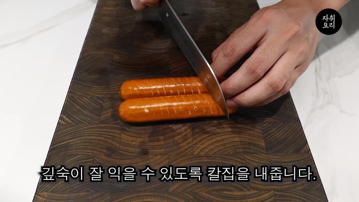 Deeply cut the sausages to ensure even cooking. Generously coat a pan with edible oil, add the sausages, and roll them until crispy.