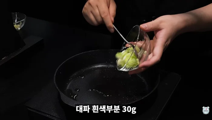 Lightly coat the pan with edible oil. Add chopped white parts of green onions and minced (or real) garlic.