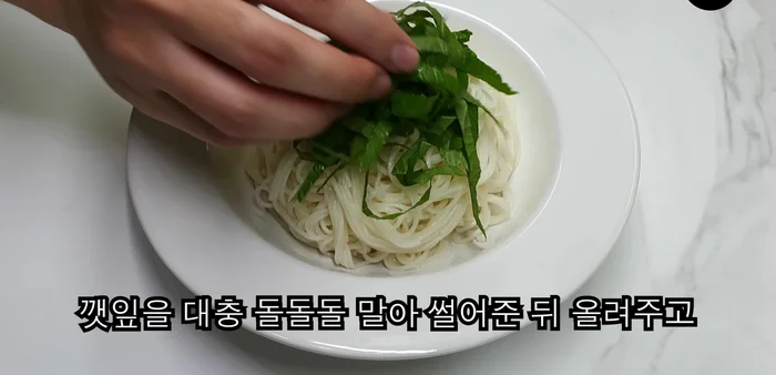 Roughly roll perilla leaves, chop, and place on noodles. Top with grilled pork.